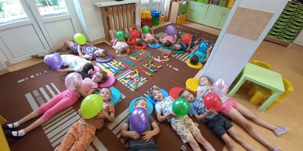 dzieci leżą na dywanie i trzymają balony.jpg